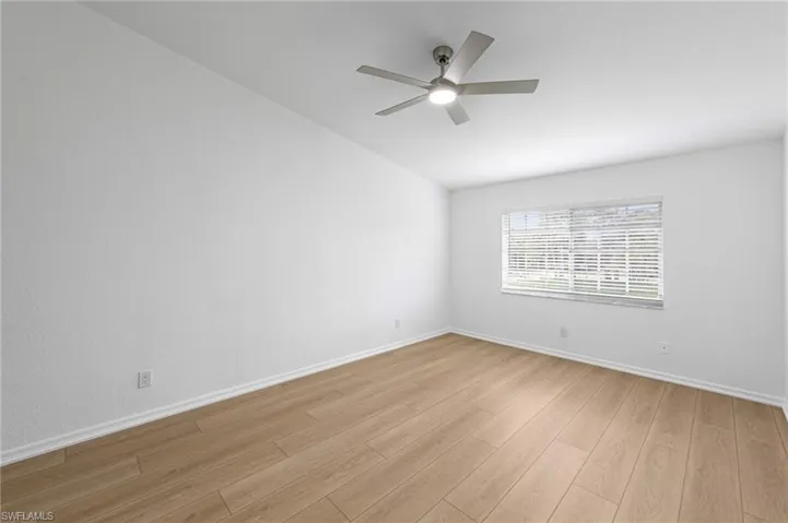 Spacious room featuring wood-finish flooring, white baseboards, and a neutral wall palette