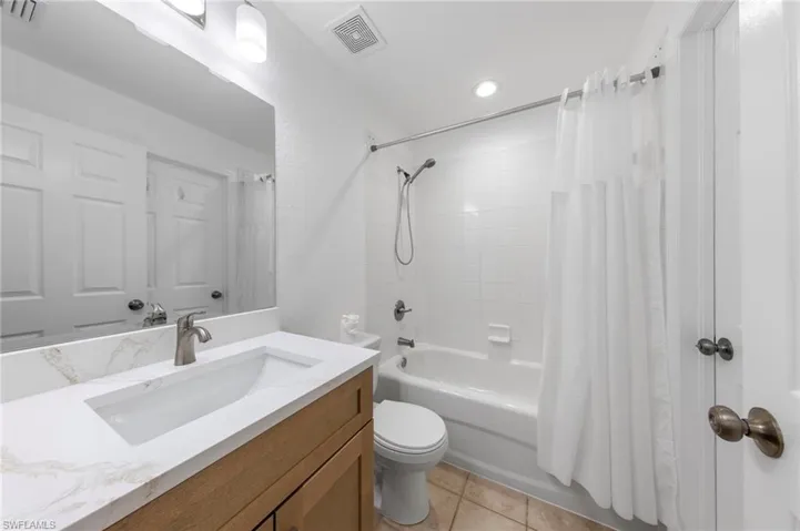 Bathroom vanity featuring a rectangular undermount sink, a stone-finish countertop, and a brushed nickel faucet