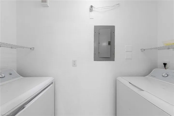 Dedicated laundry area featuring a white textured wall finish, a built-in electrical panel, and overhead wire shelving