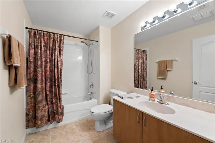 Full bathroom with tile flooring, shower / tub combo with curtain, toilet, and vanity