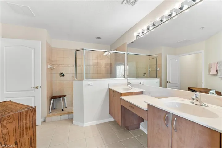 Bathroom with a shower with shower door, tile flooring, and double vanity