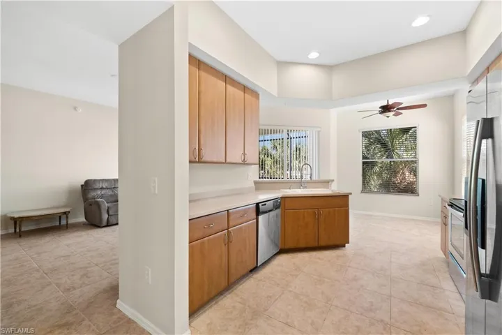 Kitchen with appliances with stainless steel finishes, sink, ceiling fan, and light tile floors