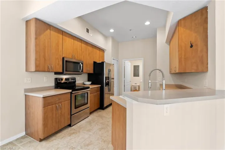 Kitchen featuring stainless steel appliances, sink, light tile flooring, and kitchen peninsula