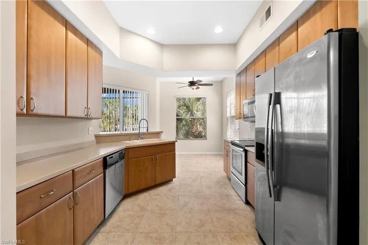 Kitchen with ceiling fan, stainless steel appliances, sink, and light tile floors