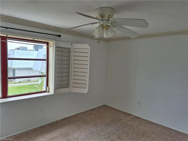Carpeted spare room with ceiling fan and crown molding