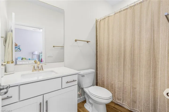 Full bath with vanity, curtained shower, and light wood-style flooring