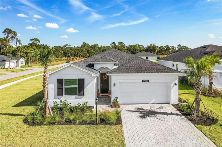 View of front of home with stucco siding, decorative driveway, a front yard, an attached garage, and roof with shingles