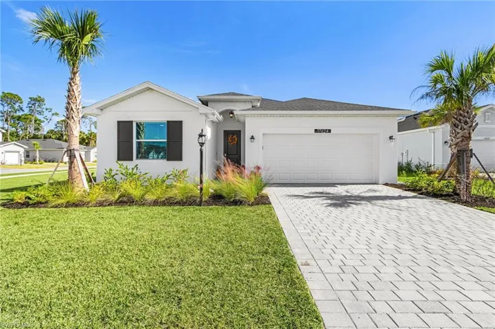 Ranch-style house featuring decorative driveway, a front lawn, stucco siding, and an attached garage