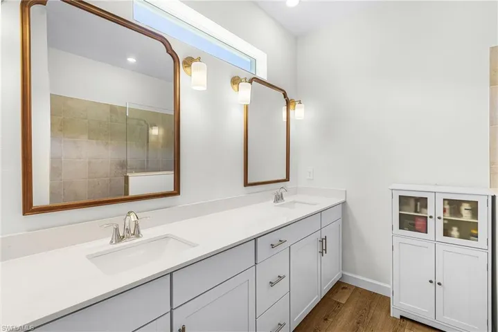 Full bathroom featuring double vanity and dark wood finished floors