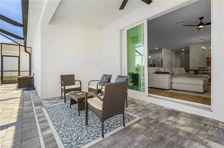 View of patio featuring ceiling fan, glass enclosure, an outdoor living space, and a sunroom
