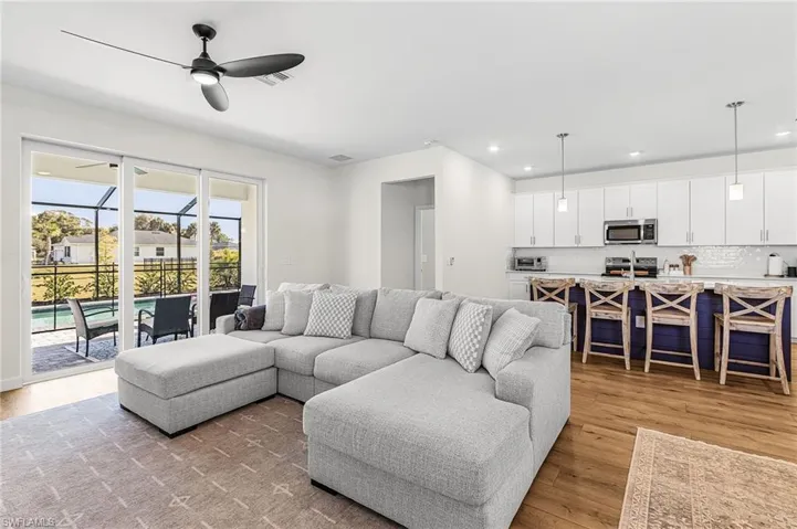 Living room featuring light wood-style floors, a ceiling fan, a sunroom, and recessed lighting