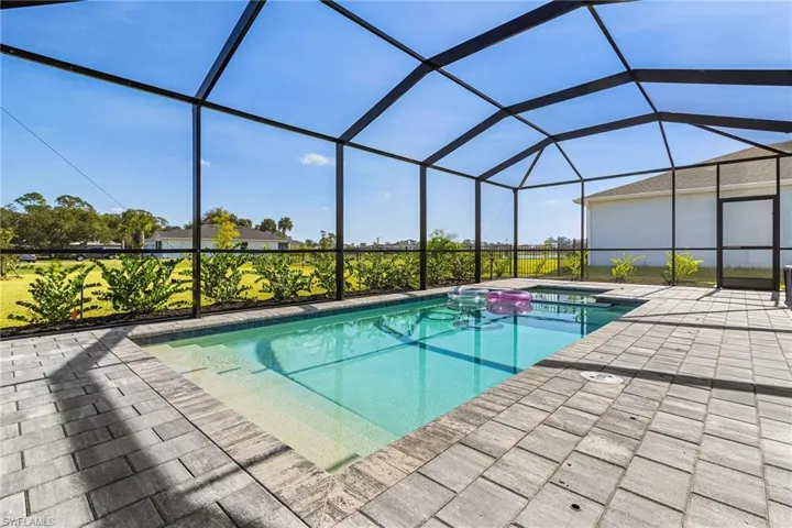 Outdoor pool with a sunroom, a lanai, a patio area, and a hot tub