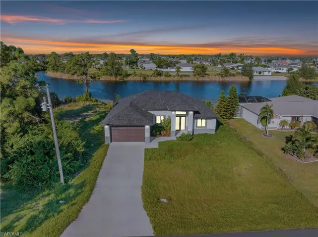 View of front facade with a front yard, a water view, an attached garage, and concrete driveway