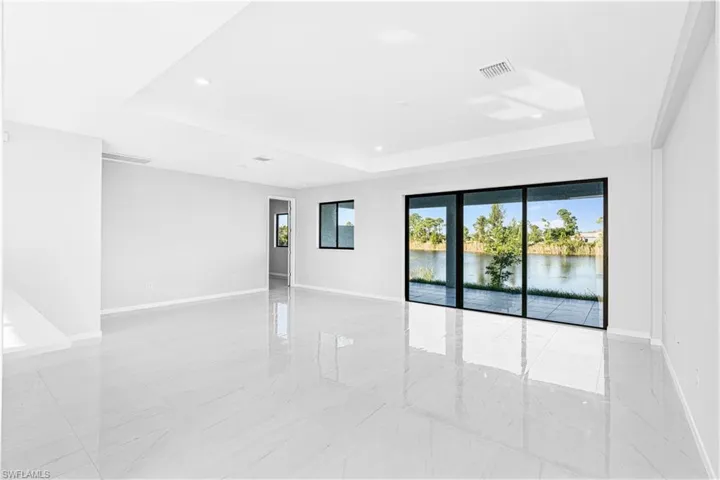 Empty room featuring a tray ceiling, a water view, and recessed lighting