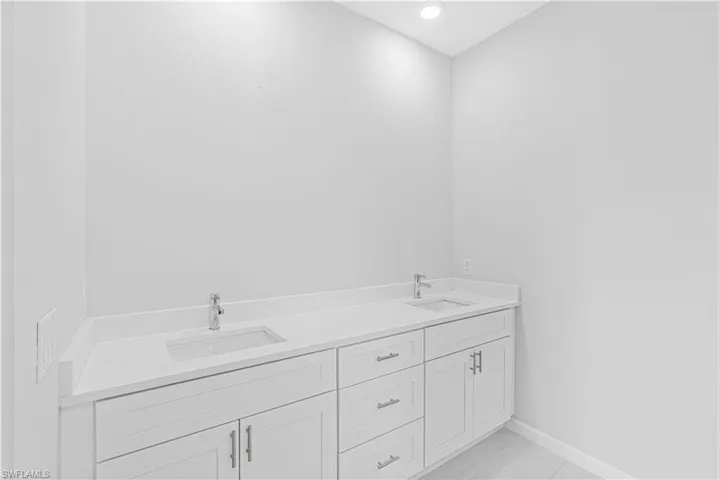 Bathroom with double vanity and baseboards