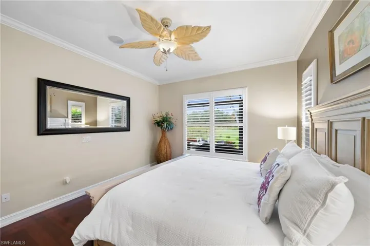 Bedroom featuring ceiling fan, wood-type flooring, and ornamental molding