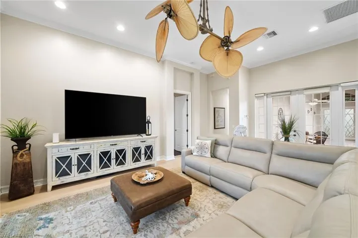 Living room featuring ornamental molding, ceiling fan, and light wood-style tile flooring