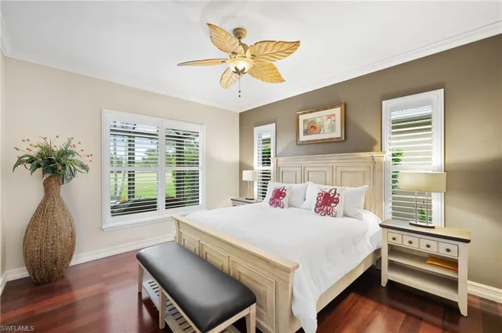 Bedroom featuring crown molding, dark / wood-style laminate floors, 2 walk-in closets