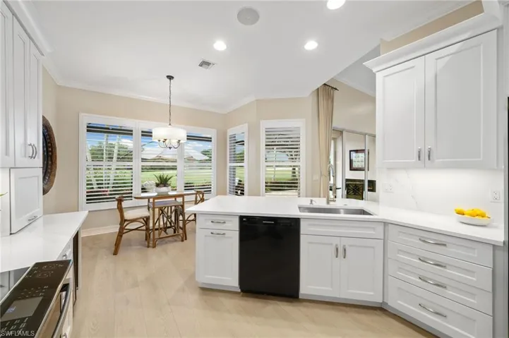Kitchen with pendant lighting, crown molding, light wood-type flooring, sink, and dishwasher