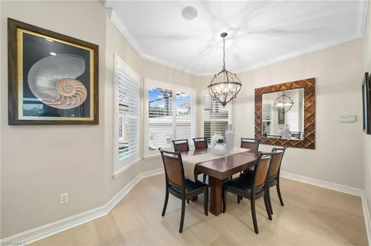 Dining space featuring an inviting chandelier, crown molding, and light wood-type flooring