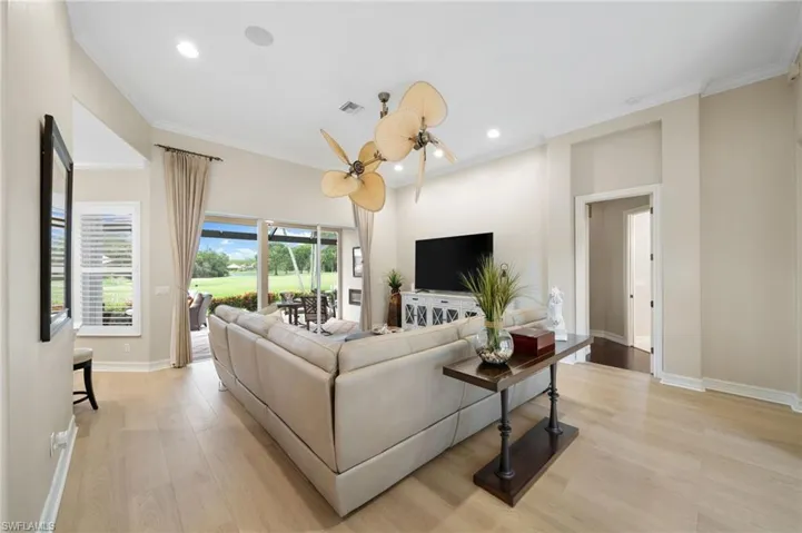Living room with ornamental molding, ceiling fan, and light hardwood / wood-style floors