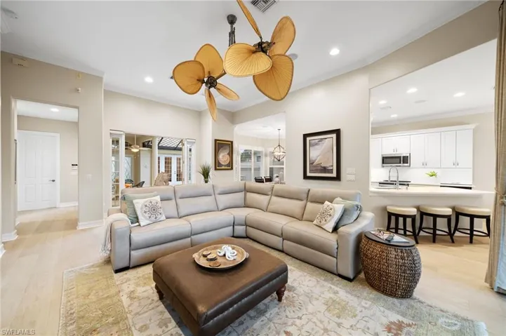 Living room featuring light wood-type flooring, ceiling fan, and ornamental molding