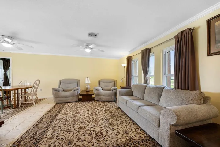 Living room featuring crown molding, a ceiling fan, and tile patterned flooring