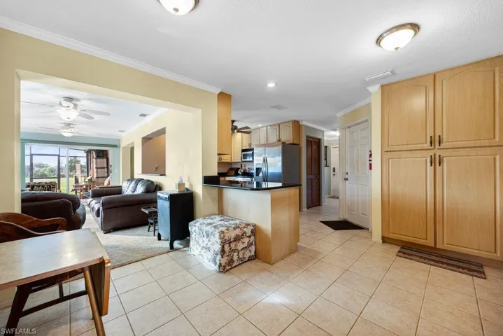 Kitchen with a ceiling fan, crown molding, open floor plan, dark countertops, and a peninsula