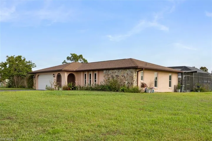 Side view front lawn, a garage, a sunroom, and stone siding