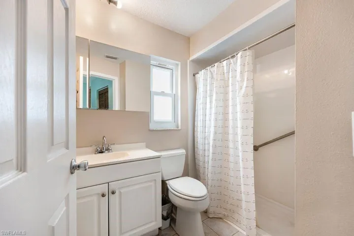Full bath featuring vanity, a shower with curtain, light tile patterned flooring, and a textured ceiling