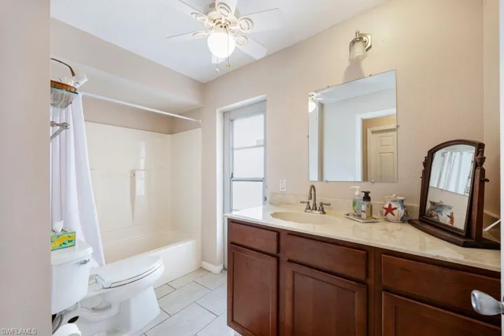 Full bathroom with vanity, shower / tub combo, light tile patterned floors, and ceiling fan