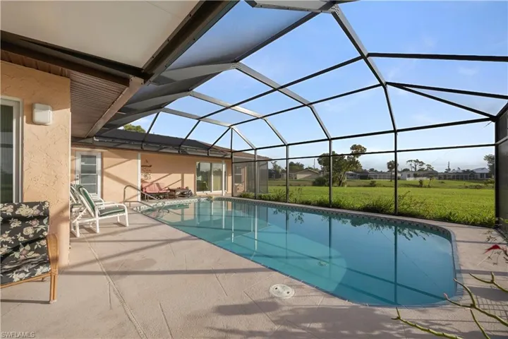 Outdoor pool with a sunroom, a patio, a yard, a lanai, and a residential view