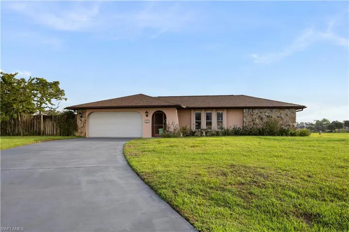 Ranch-style house with a garage, driveway, and stucco siding