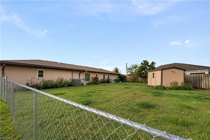 Back of property with a fenced backyard, stucco siding, and a storage shed