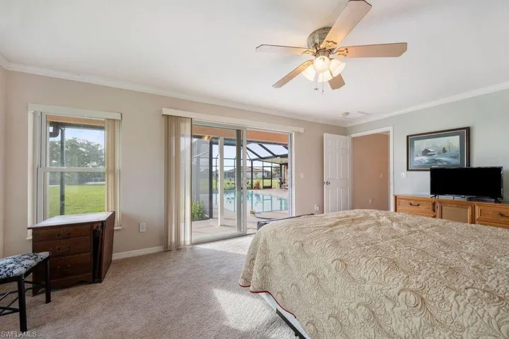 Bedroom featuring access to exterior, light colored carpet, crown molding, multiple windows, and a ceiling fan