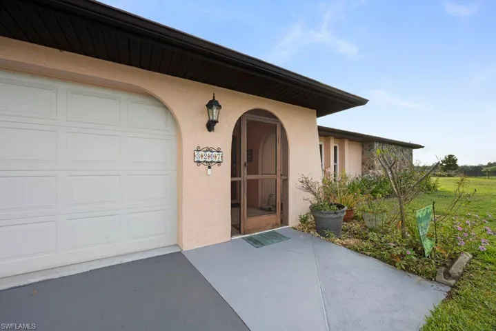 Doorway to property with stucco siding, an attached garage, a patio, and concrete driveway