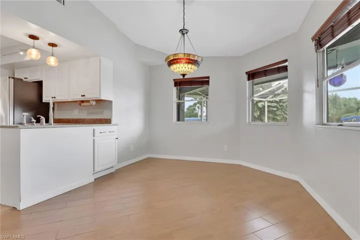 Kitchen with white cabinetry, light wood finished floors, light stone counters, pendant lighting, and a peninsula