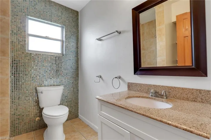 Bathroom with light tile patterned floors, vanity, and tile walls