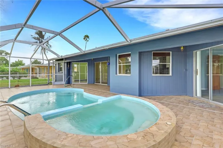 View of pool featuring a patio area, a sunroom, glass enclosure, and a pool with connected hot tub