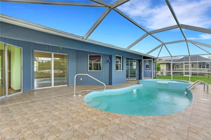 View of pool featuring a sunroom, a patio area, a pool with connected hot tub, and glass enclosure
