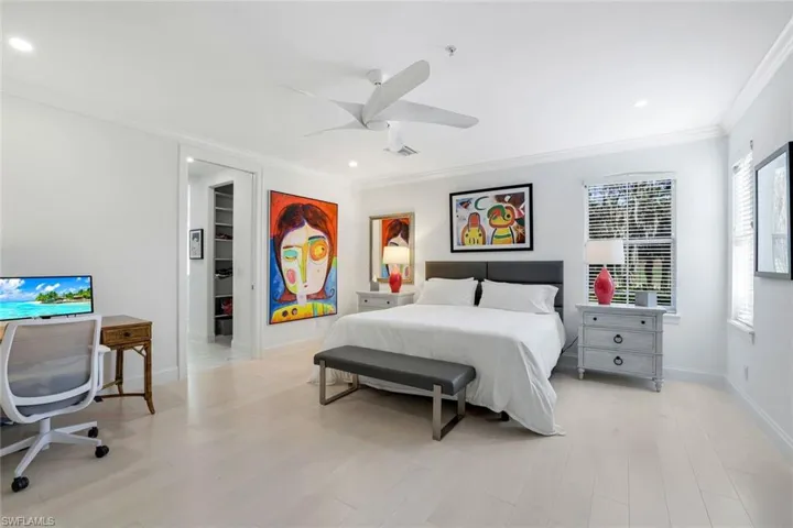 Bedroom featuring a walk in closet, ceiling fan, crown molding, light hardwood / wood-style floors, and a closet