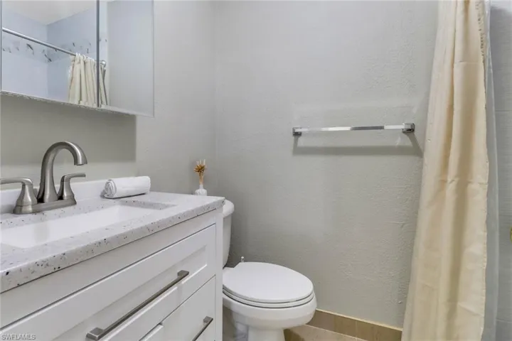 Bathroom with a textured wall, vanity, and a shower with shower curtain