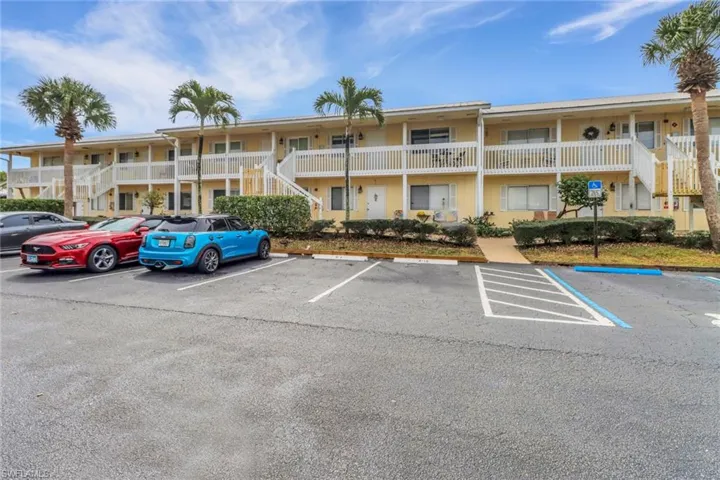 View of property with uncovered parking and stairs