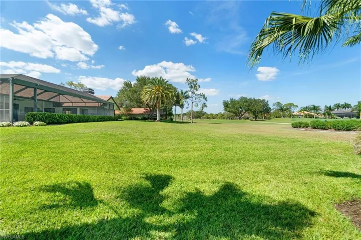 View of green lawn featuring glass enclosure and a sunroom