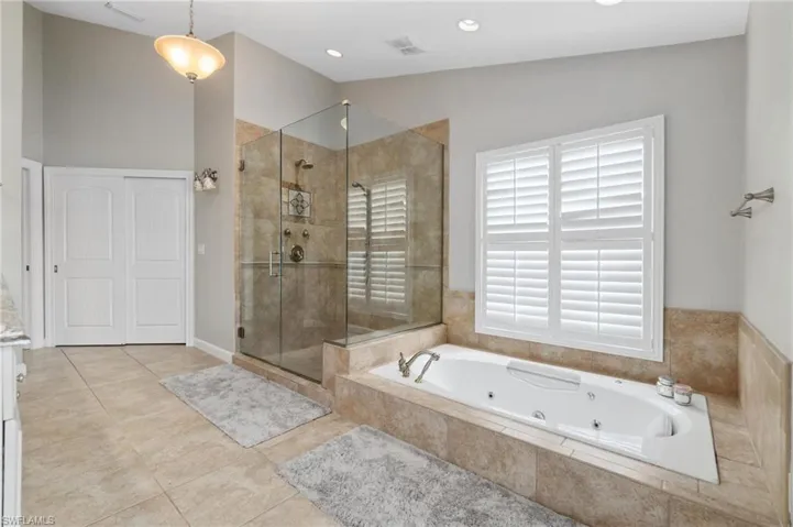 Bathroom featuring a whirlpool tub, a stall shower, light tile patterned floors, and vanity