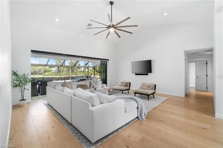 Living room featuring light wood finished floors, lofted ceiling, a sunroom, and recessed lighting