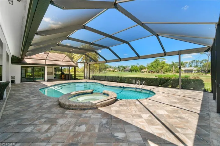 Integrated pool / hot tub featuring a sunroom, a patio area, and glass enclosure