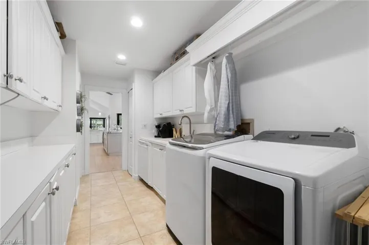 Laundry room with recessed lighting, cabinet space, washer and clothes dryer, and light tile patterned floors