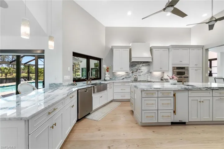 Kitchen with hanging light fixtures, light stone countertops, ceiling fan, a kitchen breakfast bar, and a high ceiling