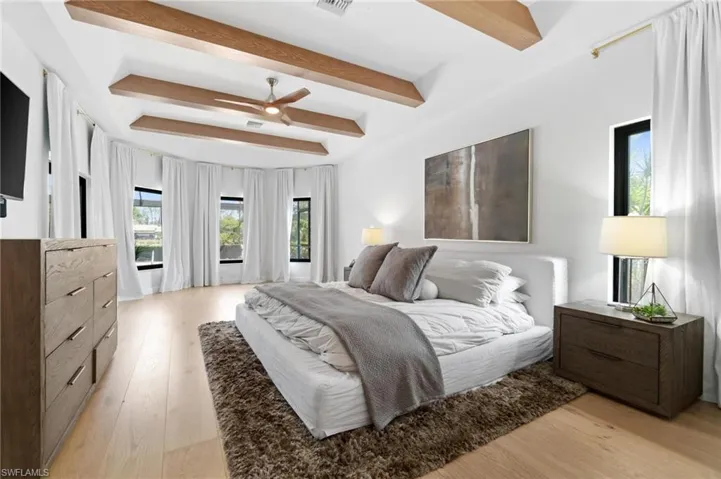 Bedroom featuring light wood-style floors, beam ceiling, and ceiling fan